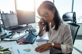 A woman answers the phone while working at a contemporary office desk,