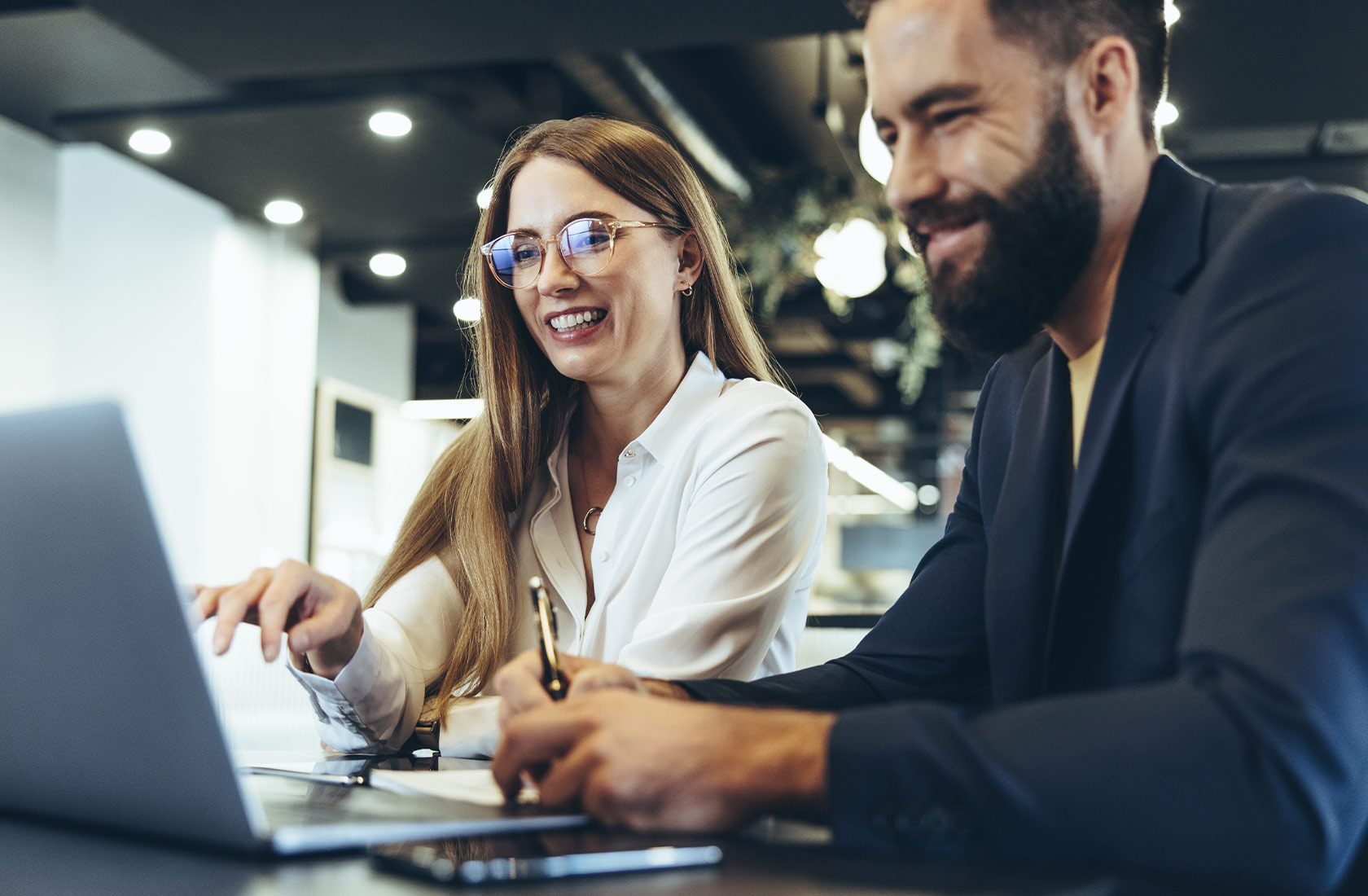 Young business man and woman work together at a laptop in a modern office