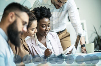 A multi-racial group of colleague discuss idea at a modern office table